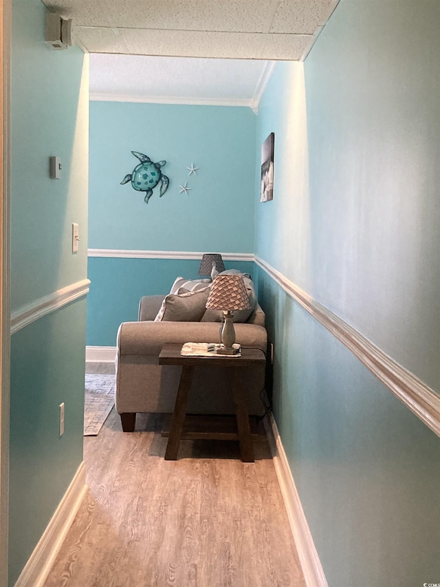 sitting room featuring a paneled ceiling, crown molding, and light wood-type flooring