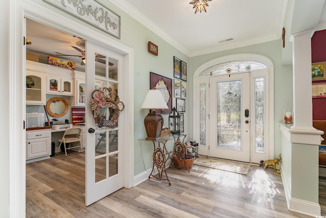 entryway with hardwood / wood-style floors, built in desk, ornamental molding, and decorative columns