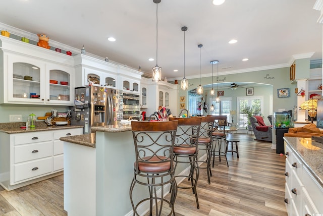 kitchen with stainless steel appliances, ceiling fan, a kitchen island, crown molding, and pendant lighting