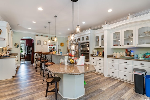 kitchen featuring pendant lighting, hardwood / wood-style floors, ornamental molding, and a center island