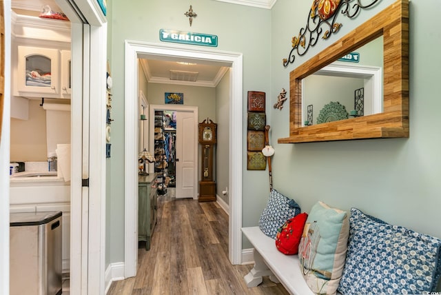 hallway with wood-type flooring, sink, and crown molding