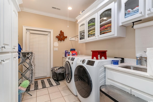 laundry room with ornamental molding, light tile patterned floors, cabinets, sink, and washing machine and dryer