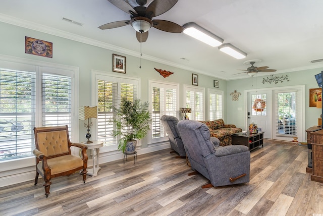 living room with ornamental molding, a wealth of natural light, wood-type flooring, and ceiling fan