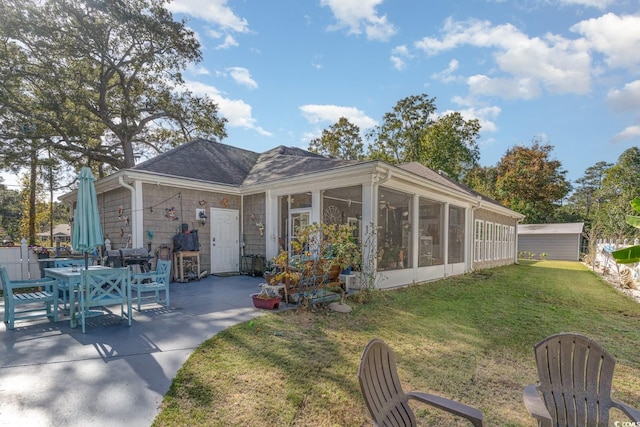 rear view of property featuring a patio area, a yard, and a sunroom