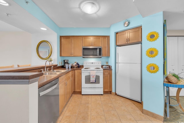 kitchen with appliances with stainless steel finishes, sink, and light tile patterned flooring