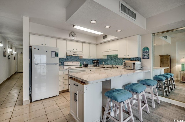 2609 S Ocean Blvd Unit 403, North Myrtle Beach, SC 29582 - kitchen with white appliances, under cabinet range hood, a sink, a peninsula, and white cabinets