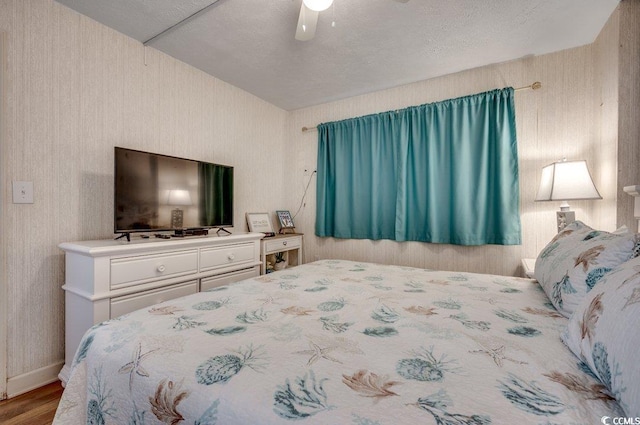 2609 S Ocean Blvd Unit 403, North Myrtle Beach, SC 29582 - bedroom featuring wood finished floors, a ceiling fan, a textured ceiling, wallpapered walls, and baseboards