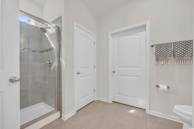 bathroom with tile patterned floors, a shower with shower door, and toilet