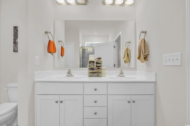 bathroom with a shower with door, vanity, and toilet