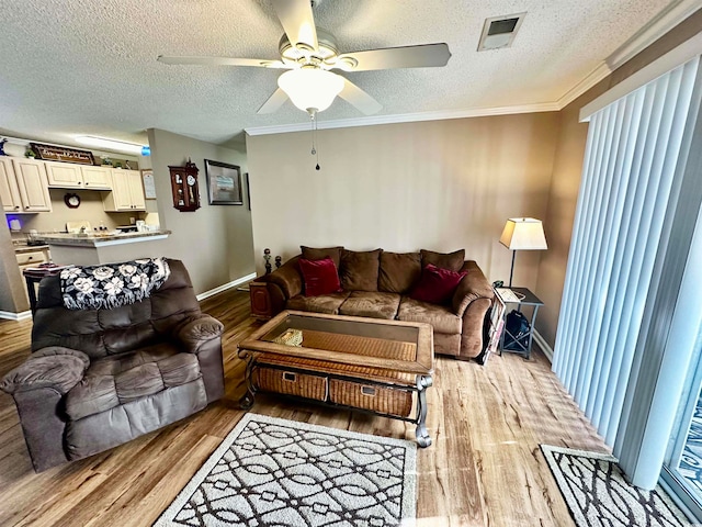 living room with ornamental molding, ceiling fan, a textured ceiling, and light hardwood / wood-style floors