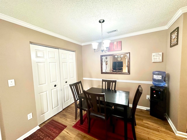 dining space with a textured ceiling, hardwood / wood-style floors, a chandelier, and crown molding