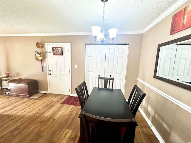 dining space featuring an inviting chandelier, hardwood / wood-style flooring, ornamental molding, and a textured ceiling