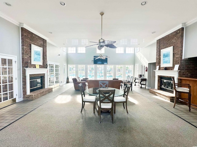 dining space featuring a brick fireplace, ceiling fan, light carpet, and ornamental molding