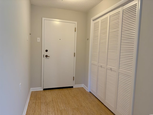 doorway to outside featuring a textured ceiling and light wood-type flooring