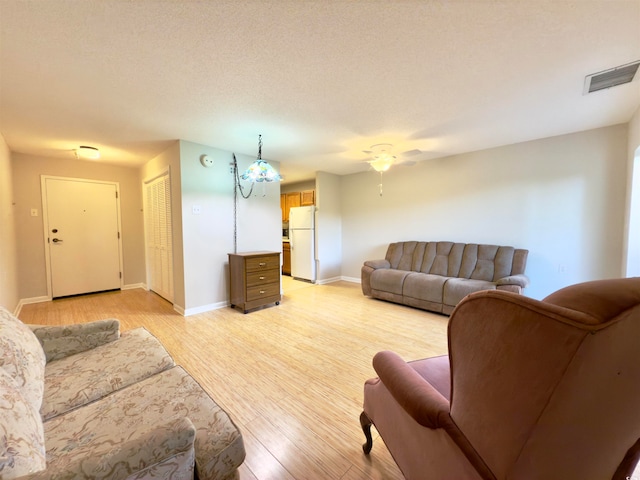 living room featuring light wood-type flooring, a textured ceiling, and ceiling fan