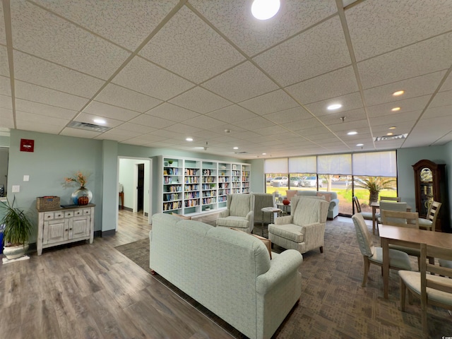 living room featuring a drop ceiling and dark wood-type flooring