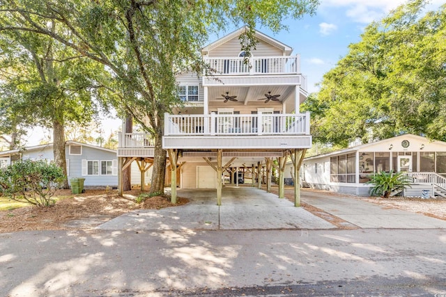 coastal home featuring a sunroom, a carport, ceiling fan, and a balcony