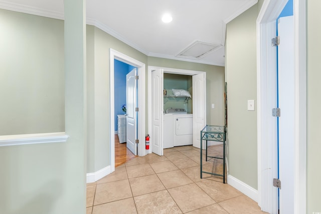 hallway with light tile patterned floors, ornamental molding, and washer / dryer