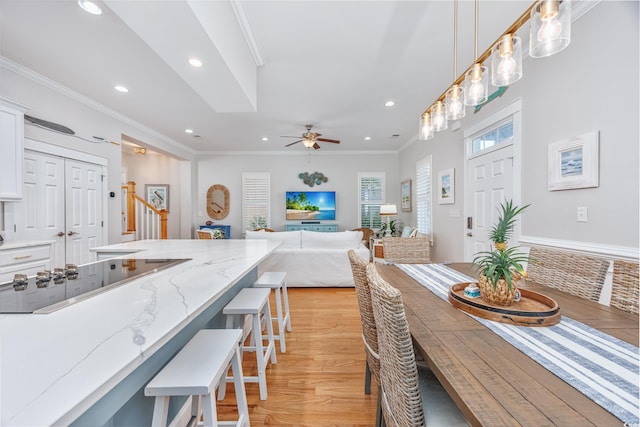 dining room featuring recessed lighting, light wood finished floors, ornamental molding, a ceiling fan, and stairway