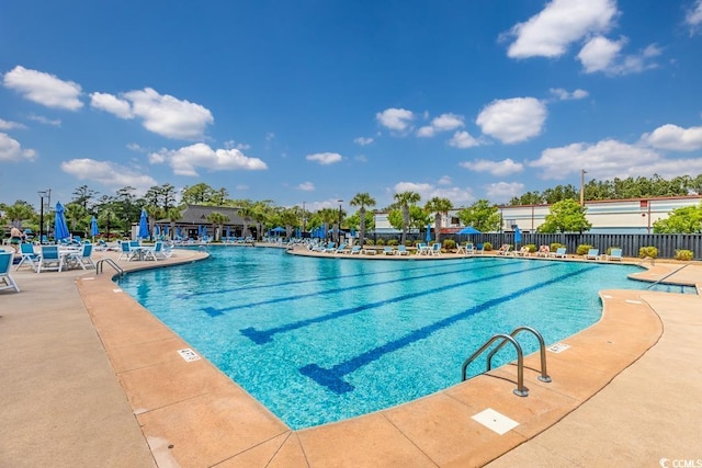 community pool with fence and a patio