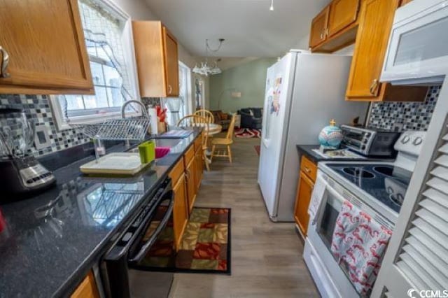 kitchen featuring light hardwood / wood-style floors, sink, white appliances, a chandelier, and decorative backsplash