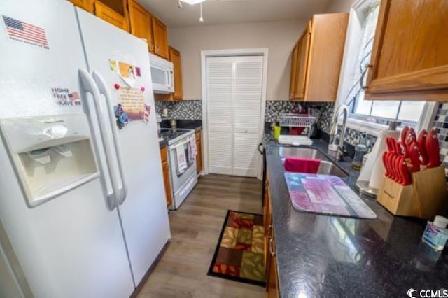 kitchen with tasteful backsplash, white appliances, sink, and light hardwood / wood-style floors