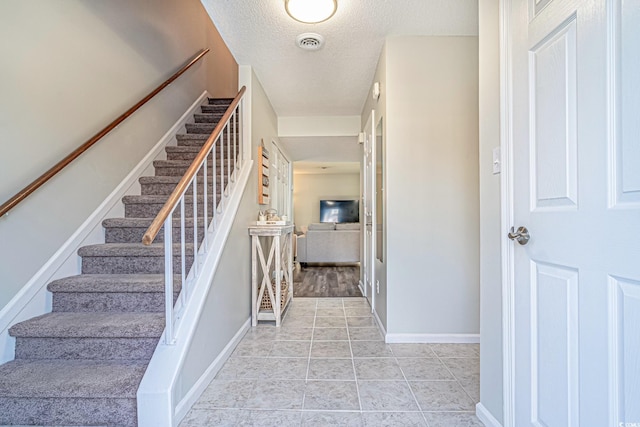 staircase featuring tile patterned flooring and a textured ceiling