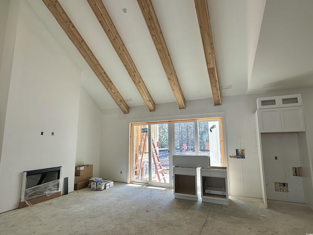 unfurnished living room featuring vaulted ceiling with beams and a glass covered fireplace