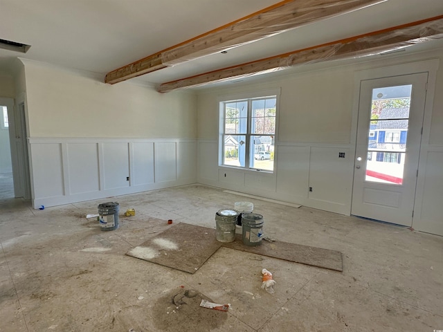 interior space with wainscoting, a healthy amount of sunlight, and beamed ceiling