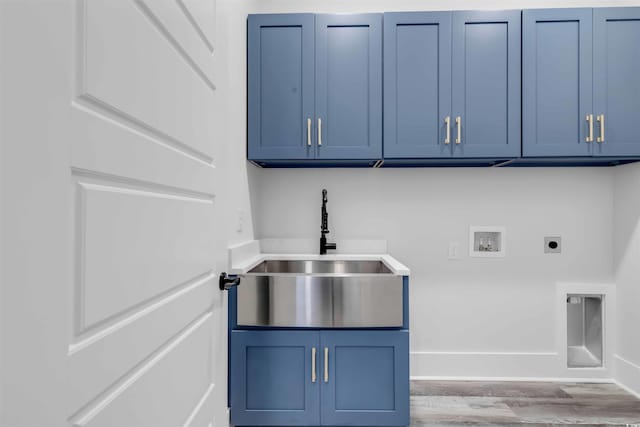 laundry room with washer hookup, cabinet space, hookup for an electric dryer, a sink, and wood finished floors