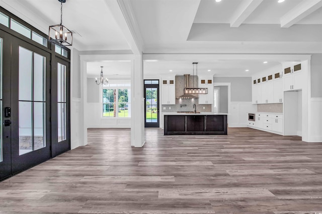 unfurnished living room with wainscoting, french doors, a notable chandelier, and beamed ceiling