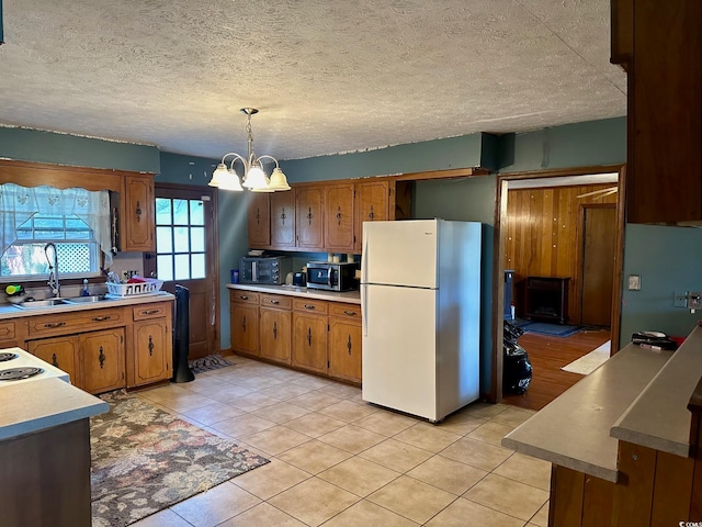 kitchen with an inviting chandelier, hanging light fixtures, sink, light tile patterned flooring, and white fridge