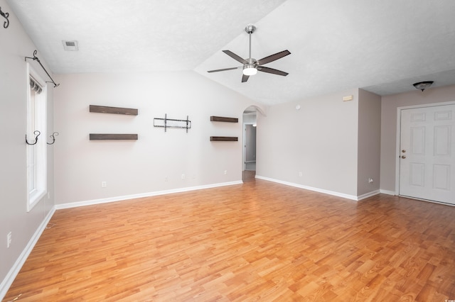 unfurnished living room with a textured ceiling, vaulted ceiling, light hardwood / wood-style flooring, and ceiling fan