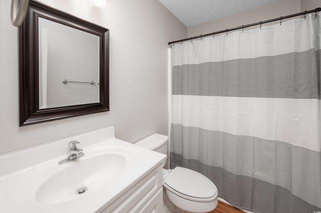 bathroom with vanity, toilet, and a textured ceiling