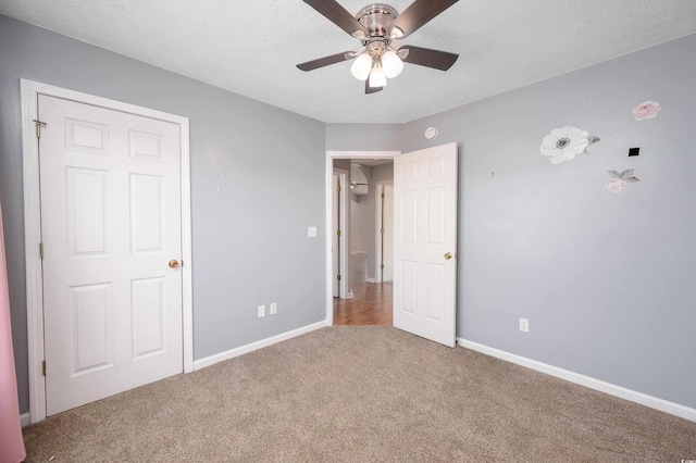 unfurnished bedroom with carpet flooring, ceiling fan, and a textured ceiling