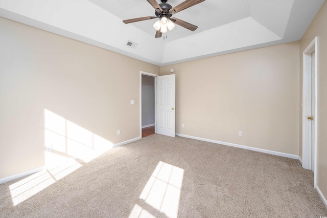 unfurnished bedroom featuring a tray ceiling, ceiling fan, and light colored carpet