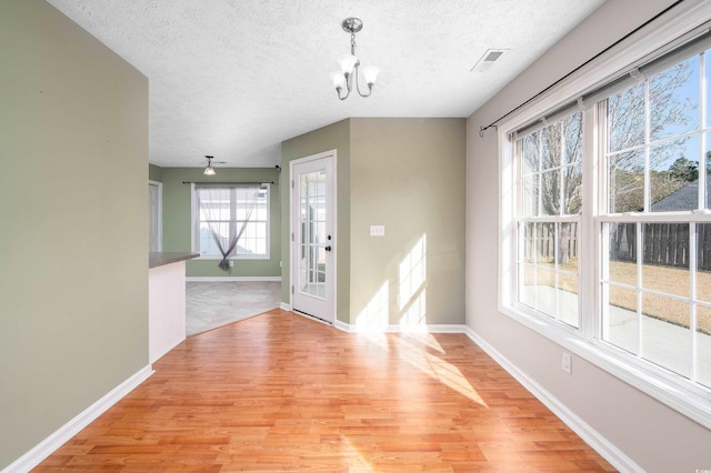 entrance foyer featuring ceiling fan with notable chandelier, a textured ceiling, and light wood-type flooring