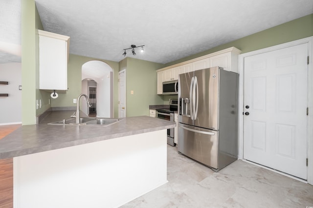 kitchen with kitchen peninsula, appliances with stainless steel finishes, a textured ceiling, and sink