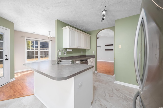 kitchen with white cabinetry, sink, kitchen peninsula, a chandelier, and appliances with stainless steel finishes