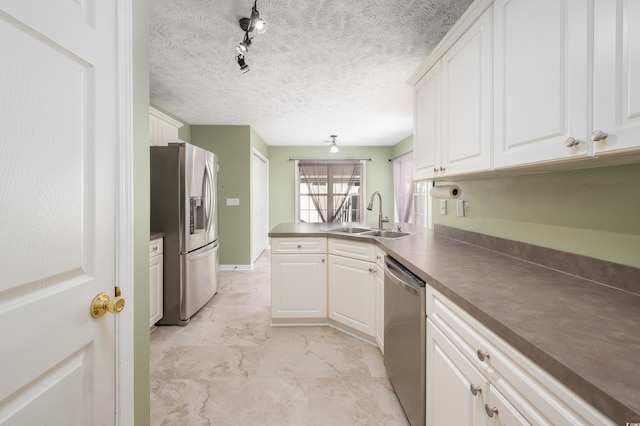 kitchen featuring rail lighting, sink, white cabinetry, kitchen peninsula, and stainless steel appliances