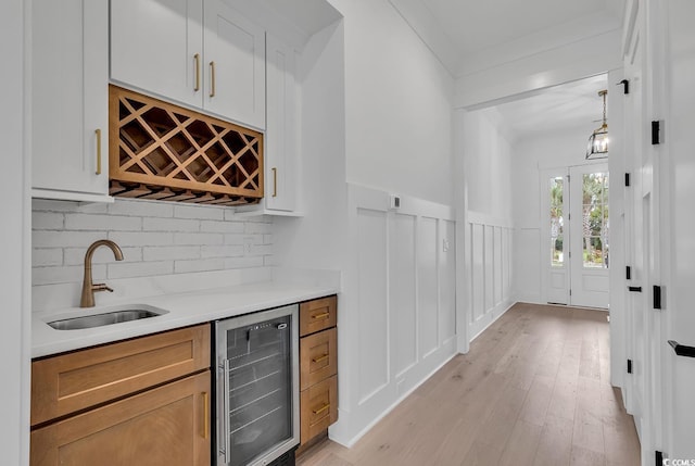 bar featuring sink, wine cooler, pendant lighting, decorative backsplash, and white cabinets