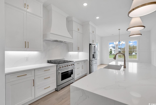 kitchen with pendant lighting, custom exhaust hood, white cabinets, sink, and stainless steel appliances