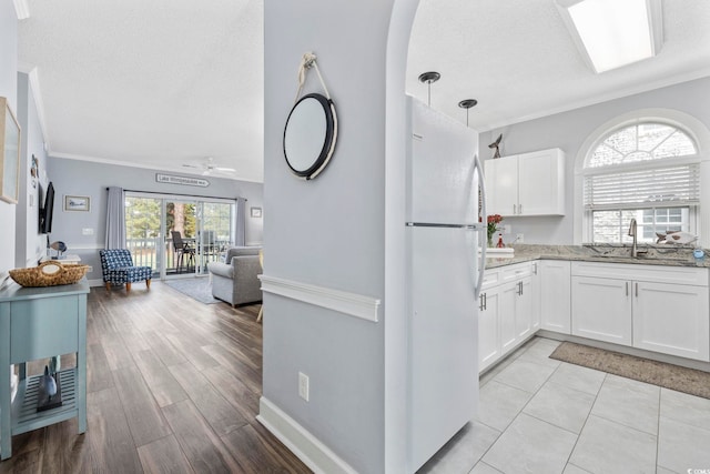 kitchen featuring white cabinets, light hardwood / wood-style floors, hanging light fixtures, and white refrigerator