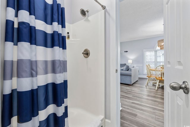 bathroom featuring a textured ceiling, hardwood / wood-style flooring, a shower with shower curtain, and crown molding