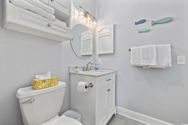 bathroom with toilet, vanity, and tile patterned flooring