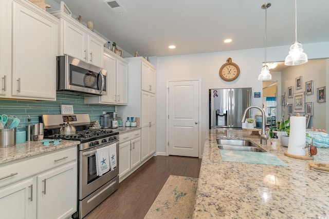 kitchen with dark wood-style floors, visible vents, a sink, decorative backsplash, and appliances with stainless steel finishes