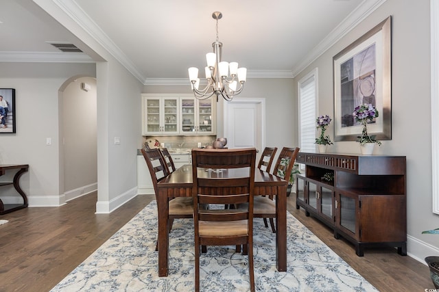 dining area with dark hardwood / wood-style flooring, an inviting chandelier, and ornamental molding