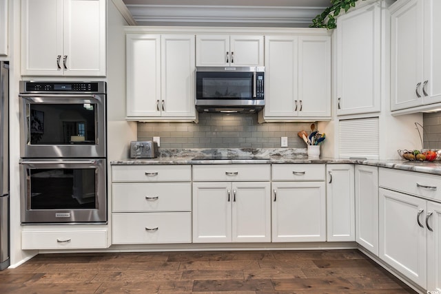 kitchen with dark wood-type flooring, white cabinets, light stone counters, and stainless steel appliances