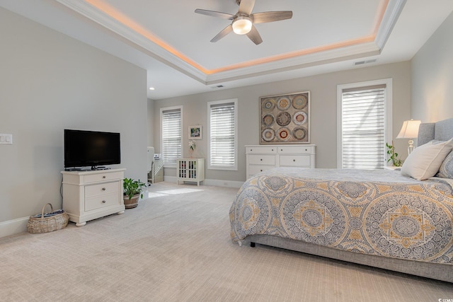 carpeted bedroom with ceiling fan, a raised ceiling, and ornamental molding