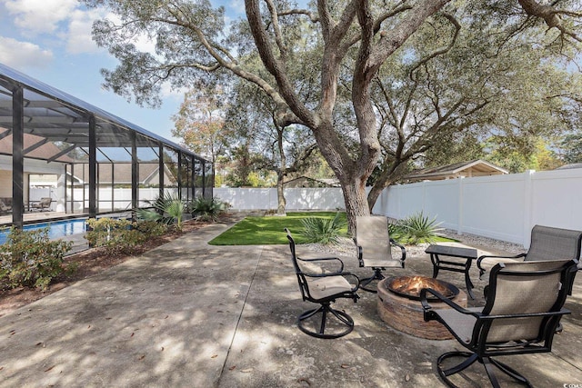 view of patio featuring a fenced in pool, glass enclosure, and an outdoor fire pit